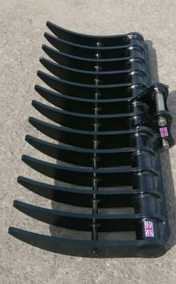 Heavy-duty steel tine rake or plough attachment with curved tines for agricultural or earthmoving equipment.