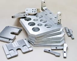 Precision-machined metal components for defence and aerospace applications, showcasing custom cutouts and complex shapes.