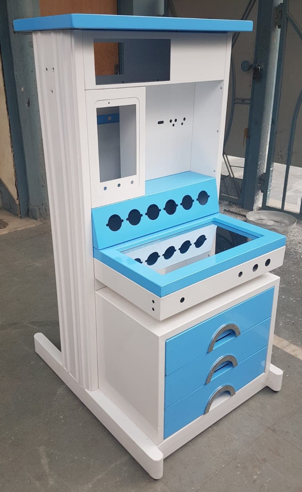Blue and white anesthesia machine trolley with drawers, control panel slots, and equipment mounting spaces.