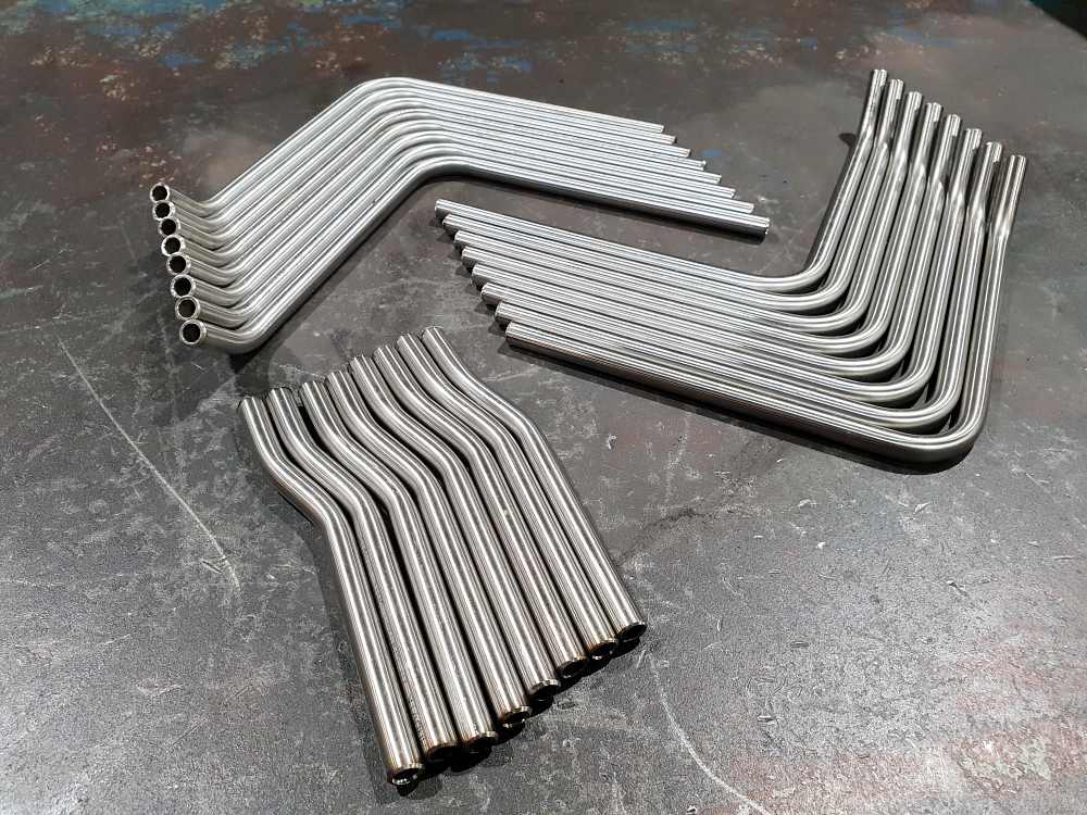 CNC-bent stainless steel pipes in various curves and angles, designed for grab bars and handrail applications.