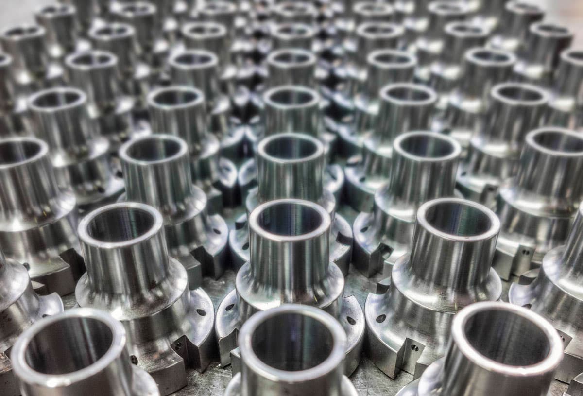 Batch of CNC-machined metal components with a polished finish, arranged uniformly for industrial application.