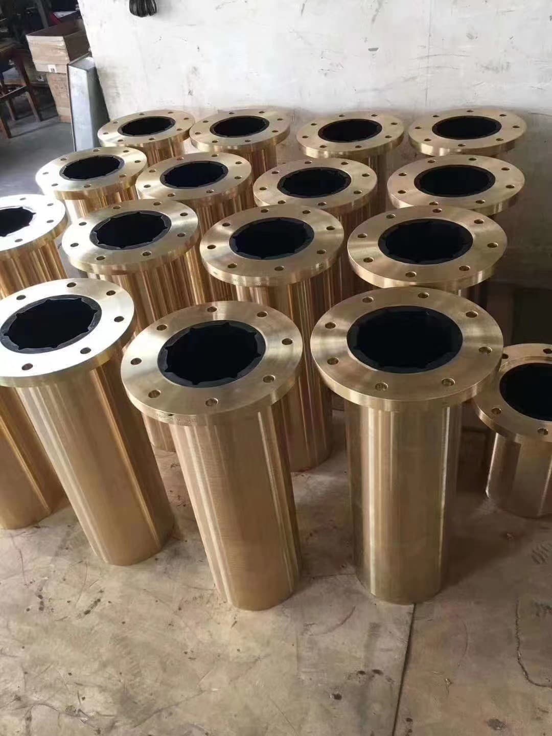 Large cylindrical bronze phenolic sleeve bearings with flanged ends, arranged vertically.