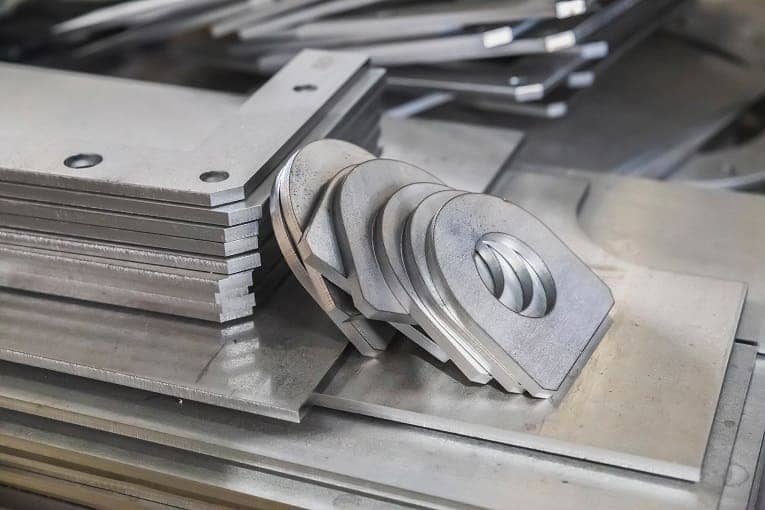 Laser-cut and machined metal brackets and plates, neatly stacked, ready for industrial assembly or fabrication use.